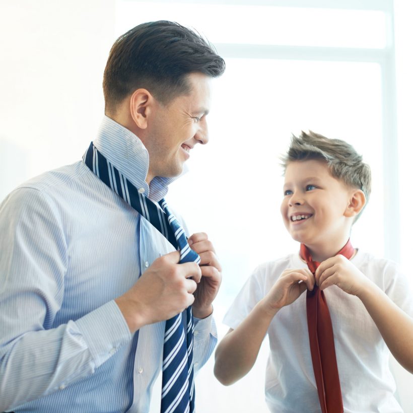 Photo of happy boy and his father tying neckties